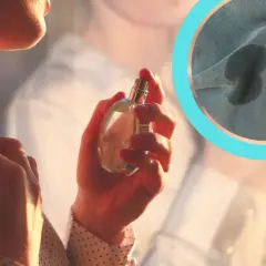 Kobieta aplikuje perfumy, a na tkaninie widoczne są ciemne plamy po perfumach.