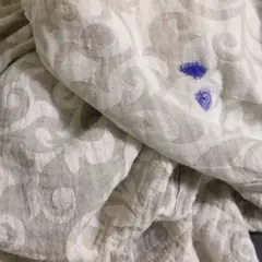 Niebieska plama po markerze na jasnej tkaninie z wzorem. Jak zmyć marker z ubrań?