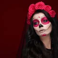 Kobieta z delikatnym makijażem na Halloween w stylu Catriny, ozdobiona czerwoną opaską z róż.