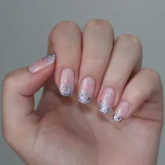 Delikatne paznokcie mleczne z brokatem na końcach, tworzące efektowny french manicure.