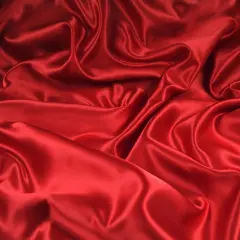 Lśniąca, czerwona tkanina, która jest **jedwabiem, co to za materiał** – miękki i elegancki, tworzący piękne fałdy.