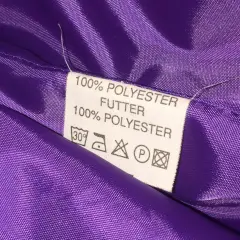 Metka z napisem "100% POLYESTER FUTTER" na fioletowej, błyszczącej podszewce. Czy poliester jest zdrowy? Pytanie pozostaje otwarte.