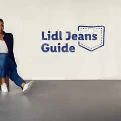Dwie kobiety w jeansach siedzą na podłodze. Obok wieszak z jeansami. Rozmiar 27 jaki to rozmiar? Sprawdź w Lidl Jeans Guide.