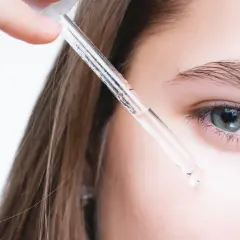 Kropla serum z retinolem i peptydami zbliża się do oka.