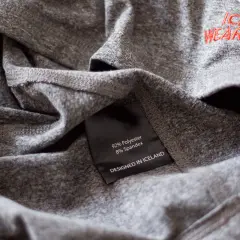 Szara koszulka z metką "92% Polyester 8% Spandex". Czy poliester się gniecie? Ta tkanina wygląda na odporną na zagniecenia.