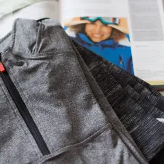 Szara bluza sportowa z zamkiem, obok książka o narciarstwie. Czy to poliamid czy poliester?