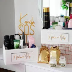 Dwa białe koszyczki z kosmetykami, idealne jako koszyczek ratunkowy. Na jednym napis "Natalia & Filip", na drugim "Kacik SOS".