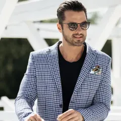 Mężczyzna w okularach przeciwsłonecznych i marynarce w kratkę. Stylowy, ale casual.