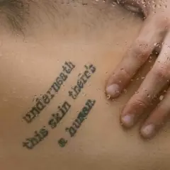 Mądre cytaty na tatuaż: "Underneath this skin there's a human". Dłoń na skórze z kroplami wody.