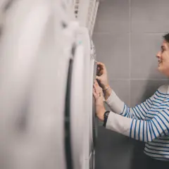 Kobieta w paski sprawdza program prania, by dowiedzieć się, w czym prać wełnę.