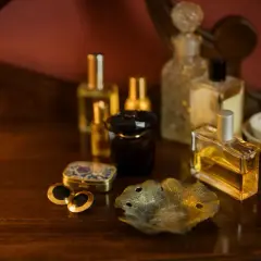 Kolekcja flakonów perfum na drewnianym blacie. Czy perfumy mają datę ważności? Zastanawiamy się nad tym, patrząc na te eleganckie buteleczki.