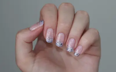 Delikatne paznokcie mleczne z brokatem na końcach, tworzące efektowny french manicure.