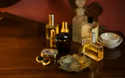 Kolekcja flakonów perfum na drewnianym blacie. Czy perfumy mają datę ważności? Zastanawiamy się nad tym, patrząc na te eleganckie buteleczki.