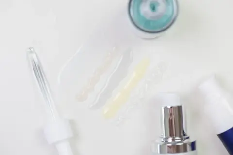 Delikatne kosmetyki z kwasem laktobionowym w ciąży. Próbki serum i kremów, pipeta i pompki dozujące.