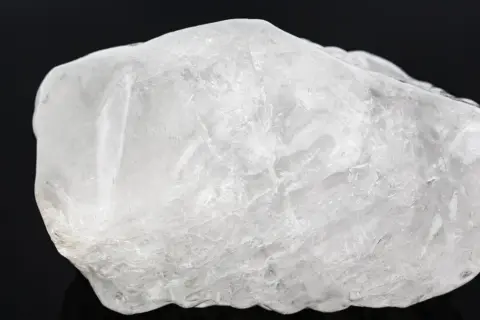 Surowy, biały ałun, minerał o krystalicznej strukturze, wygląda jak zamarznięta bryła lodu.