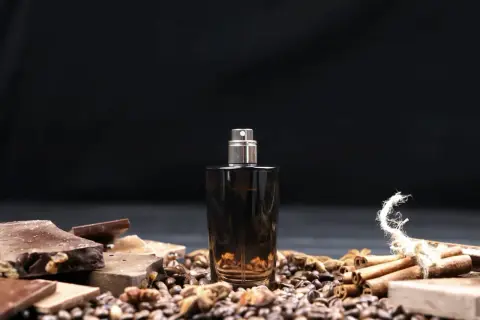 Eleganckie męskie perfumy arabskie w ciemnej butelce, otoczone kawą, czekoladą i cynamonem.