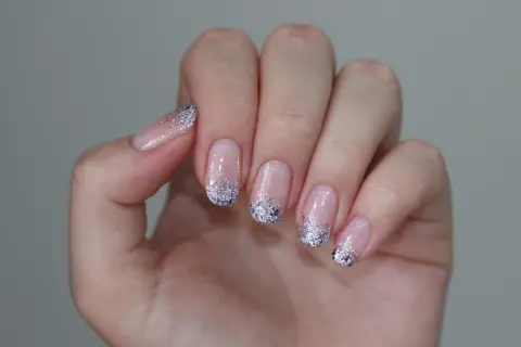 Delikatne paznokcie mleczne z brokatem na końcach, tworzące efektowny french manicure.