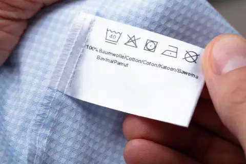 Metka z instrukcjami prania. Widoczny symbol wirowania na metce informuje o maksymalnej temperaturze wirowania.