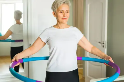 Kobieta ćwiczy z hula hop, widoczne efekty po 2 tygodniach.
