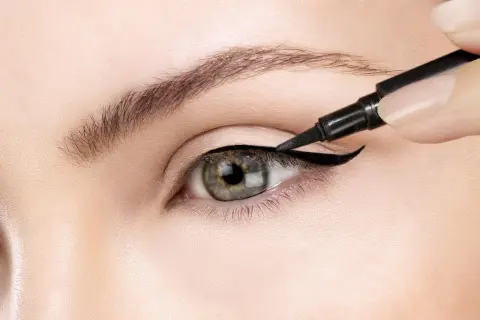Precyzyjne wykonanie kociego oka makijaż. Czarny eyeliner podkreśla kształt oka, tworząc uwodzicielskie spojrzenie.