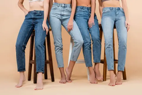 Cztery kobiety w różnych odcieniach jeansów, siedzą na stołkach. Denim to materiał, który nigdy nie wychodzi z mody.