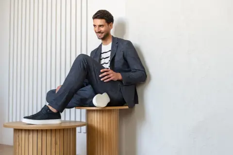 Mężczyzna w granatowym garniturze i białej bluzce w paski, prezentujący styl smart casual męski.