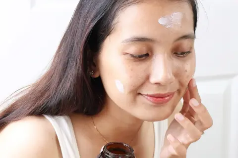 Kobieta aplikuje krem Purito Panthenol Cream na twarz, dbając o nawilżenie skóry.