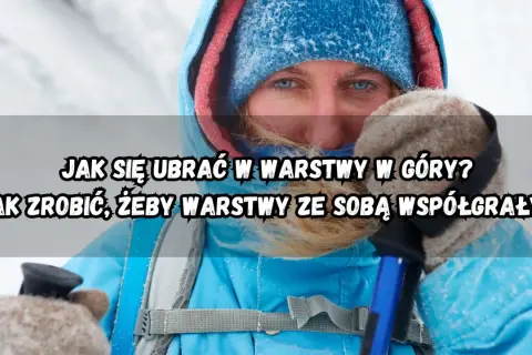 Kobieta w zimowej kurtce i czapce, z niebieskimi oczami, przygotowuje się do wędrówki. Dowiedz się, jak ubrać się w góry warstwowo.