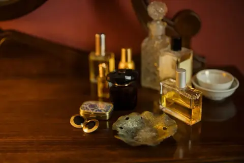 Kolekcja flakonów perfum na drewnianym blacie. Czy perfumy mają datę ważności? Zastanawiamy się nad tym, patrząc na te eleganckie buteleczki.