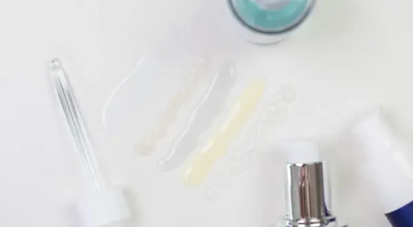 Delikatne kosmetyki z kwasem laktobionowym w ciąży. Próbki serum i kremów, pipeta i pompki dozujące.