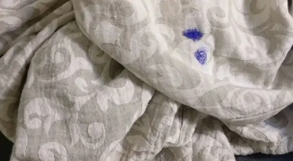 Niebieska plama po markerze na jasnej tkaninie z wzorem. Jak zmyć marker z ubrań?