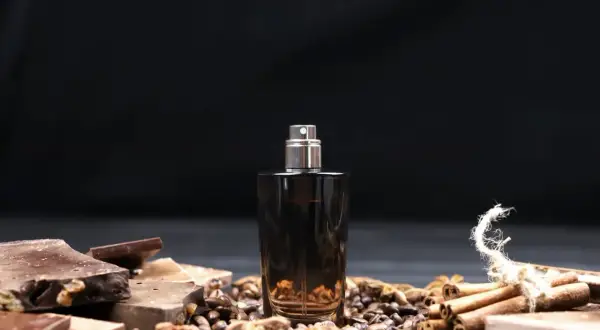 Eleganckie męskie perfumy arabskie w ciemnej butelce, otoczone kawą, czekoladą i cynamonem.