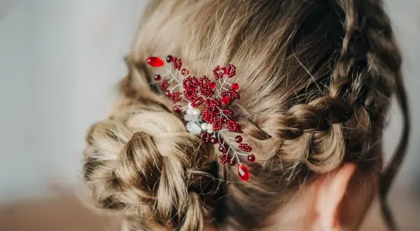 Eleganckie fryzury komunijne z warkoczem i ozdobą z czerwonych koralików. Delikatny warkocz oplata głowę, tworząc romantyczną całość.