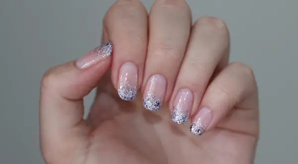 Delikatne paznokcie mleczne z brokatem na końcach, tworzące efektowny french manicure.