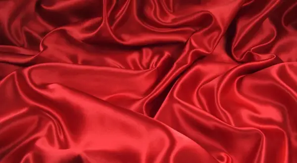 Lśniąca, czerwona tkanina, która jest **jedwabiem, co to za materiał** – miękki i elegancki, tworzący piękne fałdy.