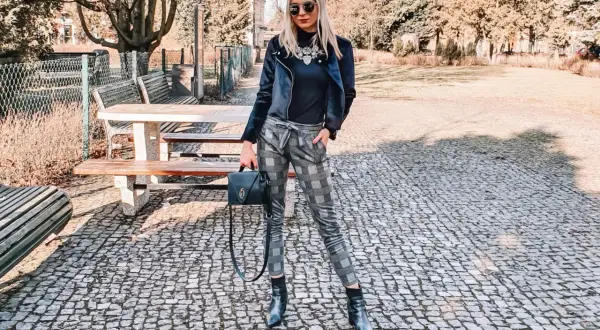 Stylowa kobieta w spodniach w kratę, czarnej ramonesce i botkach. Idealna stylizacja damska na jesienny spacer.