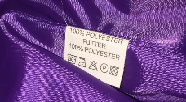 Metka z napisem "100% POLYESTER FUTTER" na fioletowej, błyszczącej podszewce. Czy poliester jest zdrowy? Pytanie pozostaje otwarte.