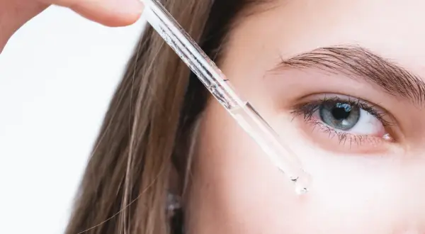 Kropla serum z retinolem i peptydami zbliża się do oka.