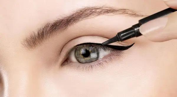 Precyzyjne wykonanie kociego oka makijaż. Czarny eyeliner podkreśla kształt oka, tworząc uwodzicielskie spojrzenie.