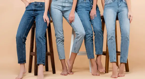 Cztery kobiety w różnych odcieniach jeansów, siedzą na stołkach. Denim to materiał, który nigdy nie wychodzi z mody.