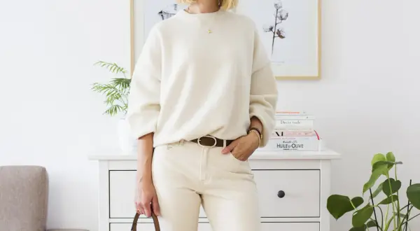Eleganckie biały sweter stylizacje: luźny sweter, beżowe spodnie, brązowy pasek i torebka.