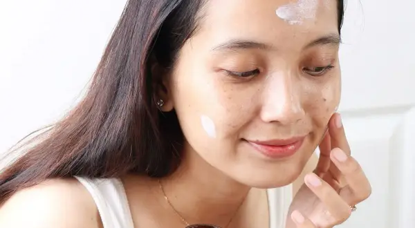 Kobieta aplikuje krem Purito Panthenol Cream na twarz, dbając o nawilżenie skóry.