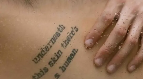 Mądre cytaty na tatuaż: "Underneath this skin there's a human". Dłoń na skórze z kroplami wody.