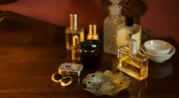 Kolekcja flakonów perfum na drewnianym blacie. Czy perfumy mają datę ważności? Zastanawiamy się nad tym, patrząc na te eleganckie buteleczki.