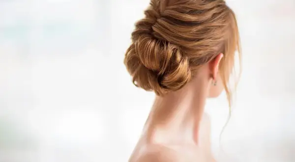 Eleganckie, delikatne upięcie rozpuszczonych włosów w kok. Włosy w odcieniu miodowego blondu.