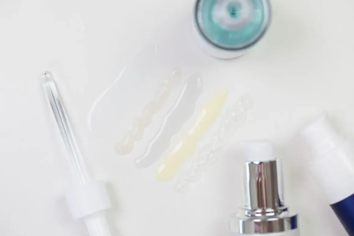 Delikatne kosmetyki z kwasem laktobionowym w ciąży. Próbki serum i kremów, pipeta i pompki dozujące.