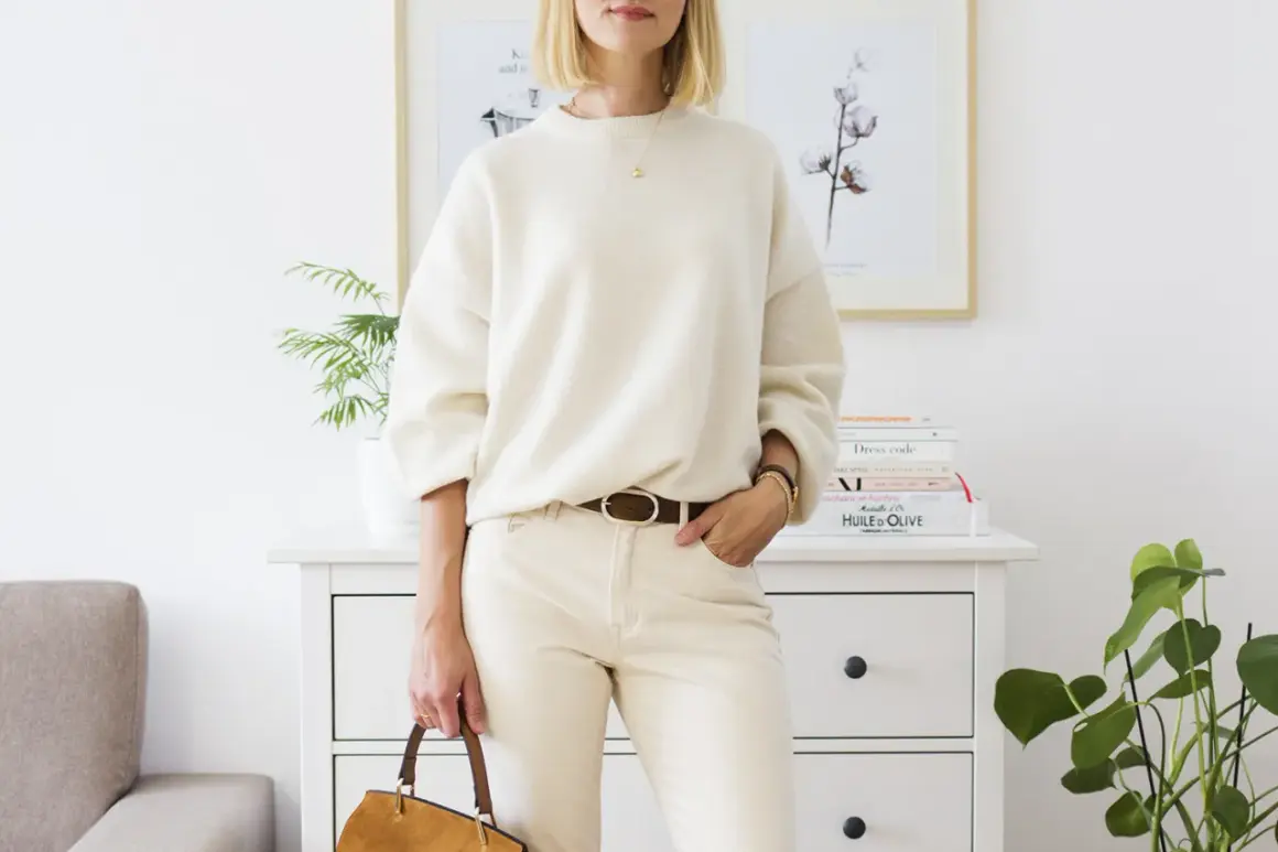 Eleganckie biały sweter stylizacje: luźny sweter, beżowe spodnie, brązowy pasek i torebka.