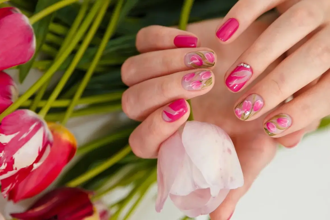 Dłonie z manicurem french zdobionym motywem tulipanów. Delikatne kwiaty na paznokciach idealnie komponują się z bukietem świeżych kwiatów.