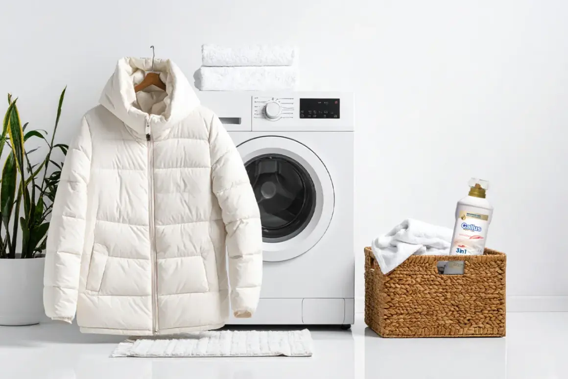 Biała kurtka puchowa wisi obok pralki, gotowa na pranie. W koszyku obok znajduje się detergent do prania.