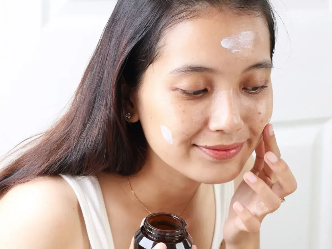 Kobieta aplikuje krem Purito Panthenol Cream na twarz, dbając o nawilżenie skóry.